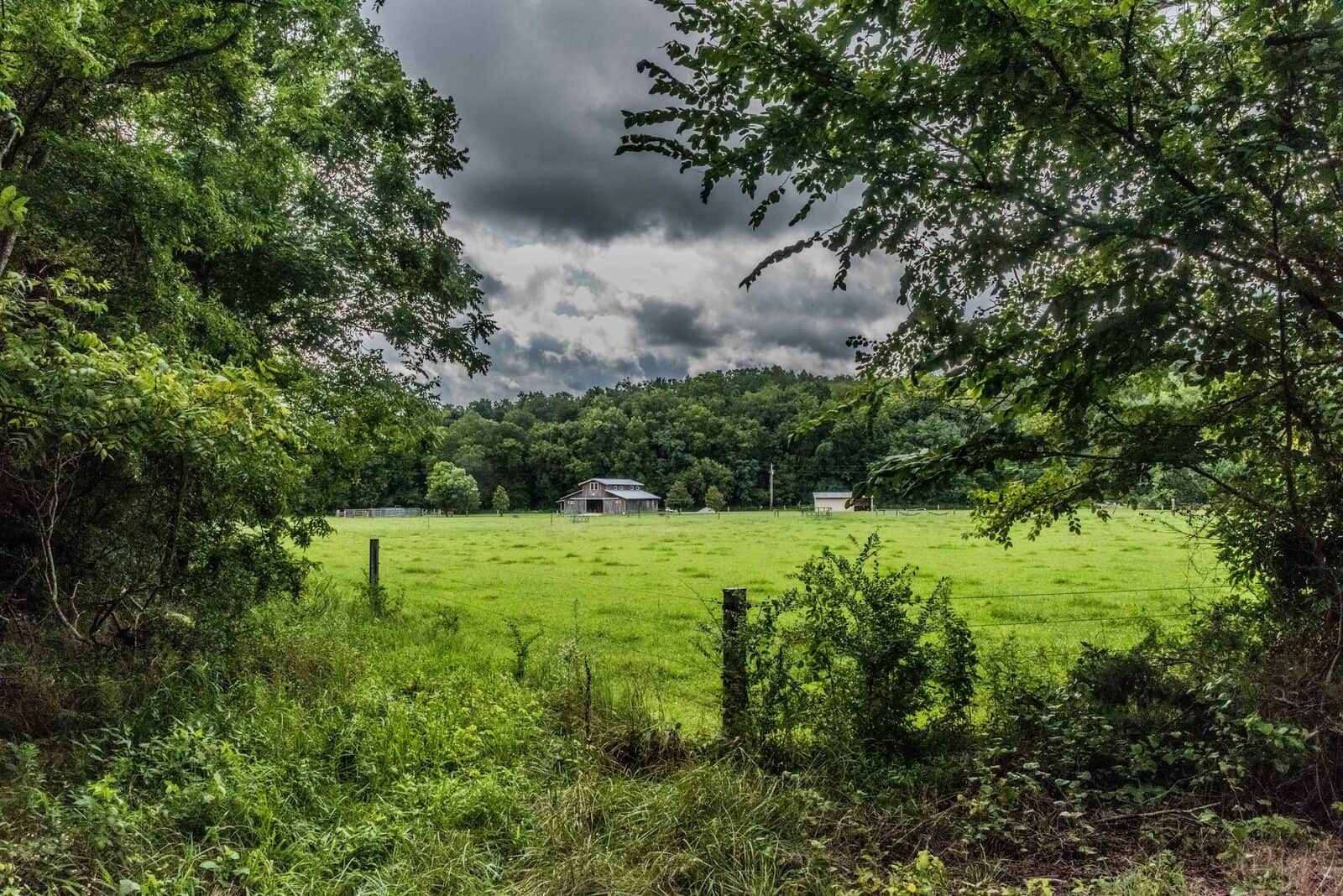A barn beyond a green pasture in the Middle Tennessee countryside