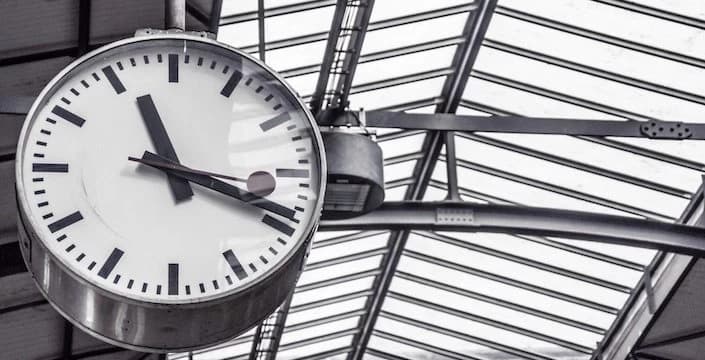 Close-up of a station clock beneath a glass roof