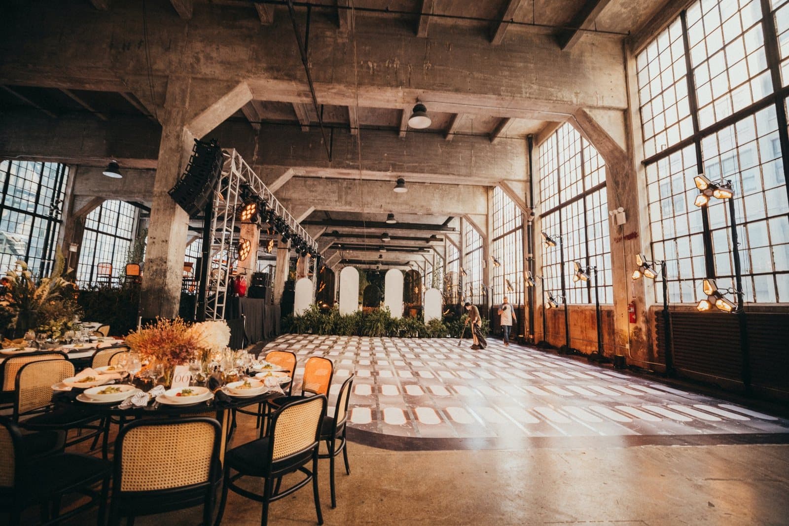 Round dinner tables set in a tall-windowed warehouse hall at Industry City, Sunset Park, Brooklyn