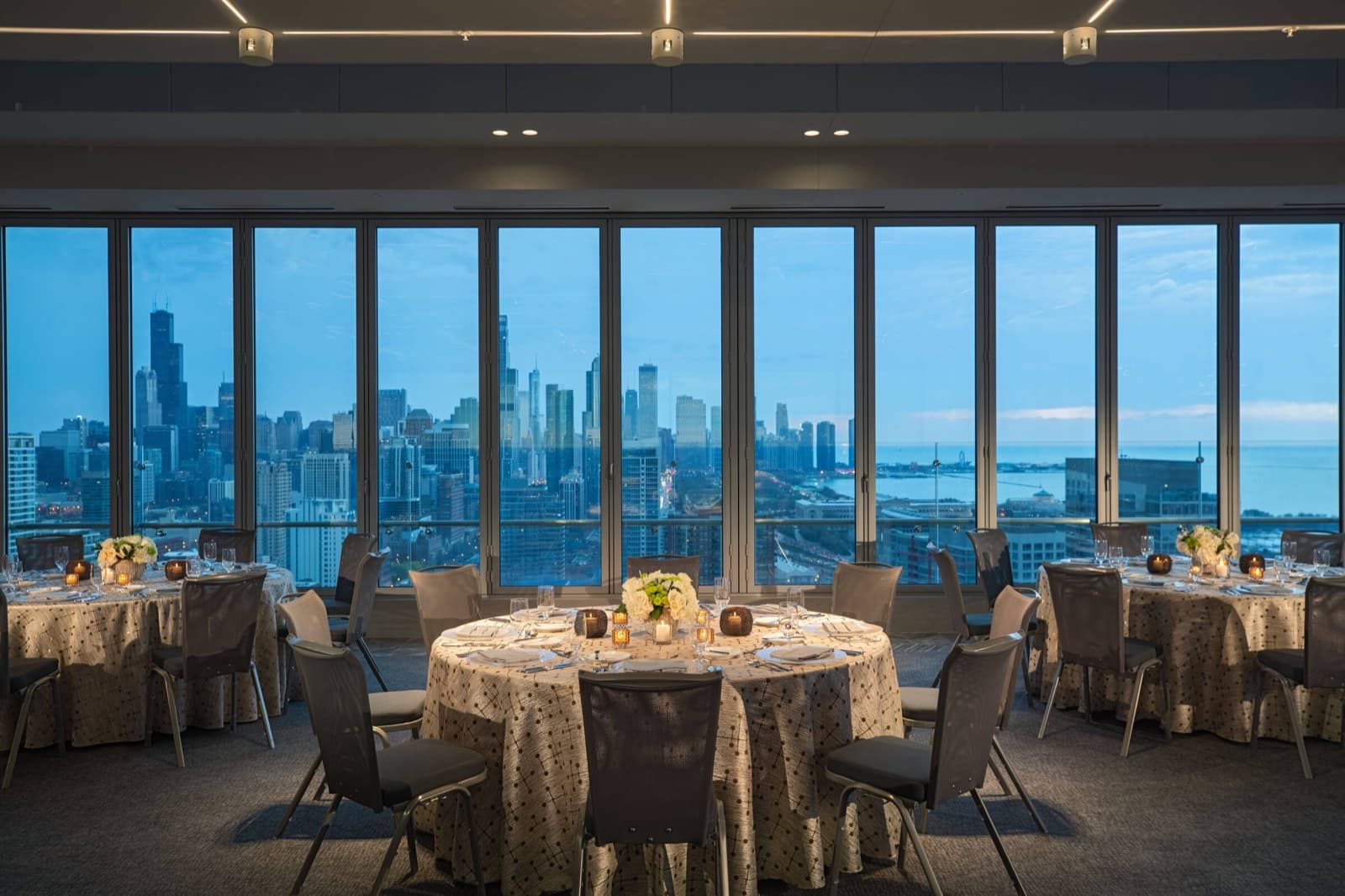A Marriott Marquis Chicago event room set with banquet rounds, the skyline and Lake Michigan in the windows