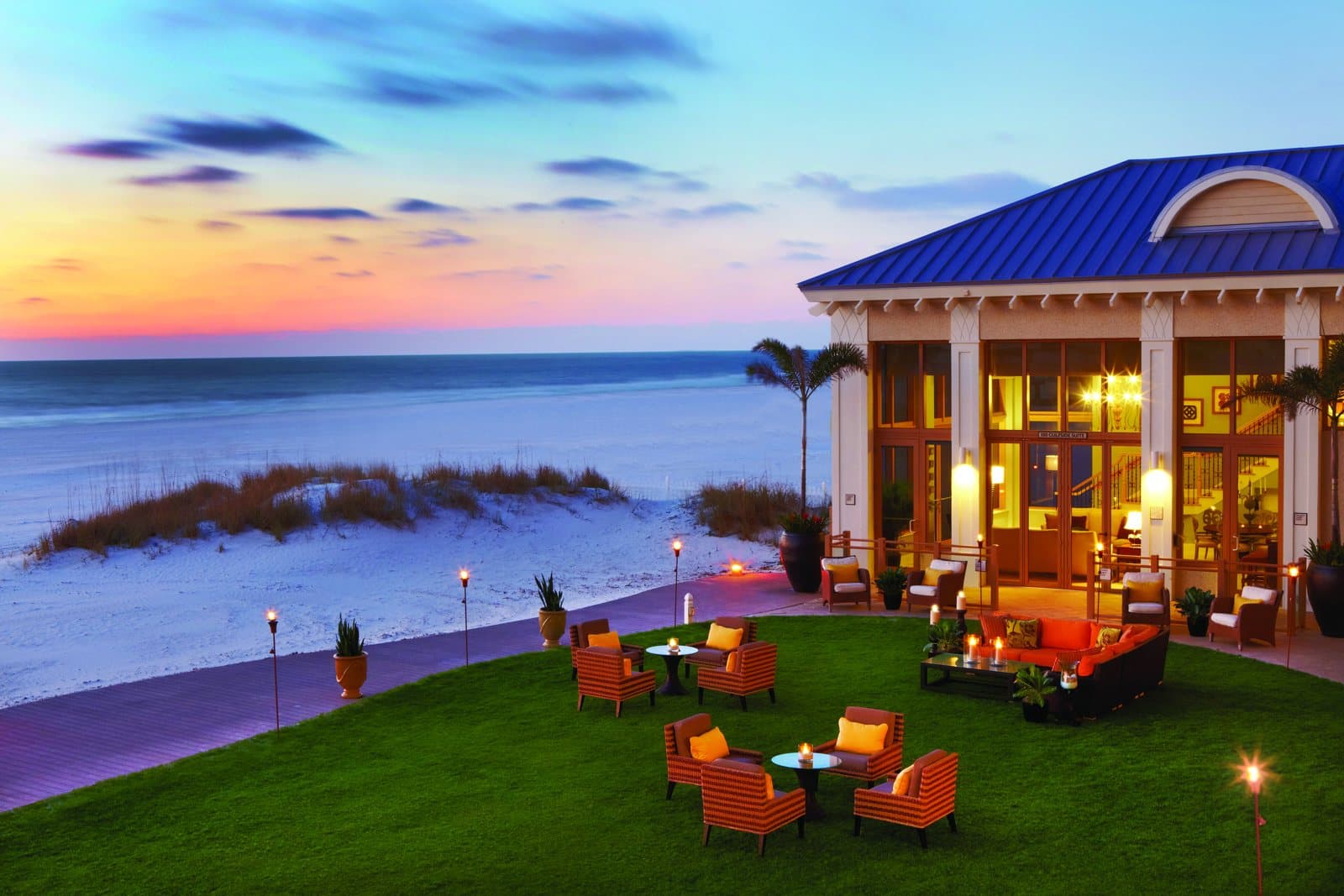 Gulf-front lawn with lounge seating and tiki torches at sunset at Sandpearl Resort, Clearwater Beach, FL
