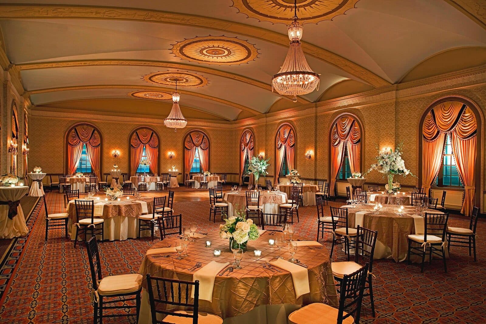 The Westin Poinsett's Gold Ballroom, with chandeliers and draped arched windows, set with round tables