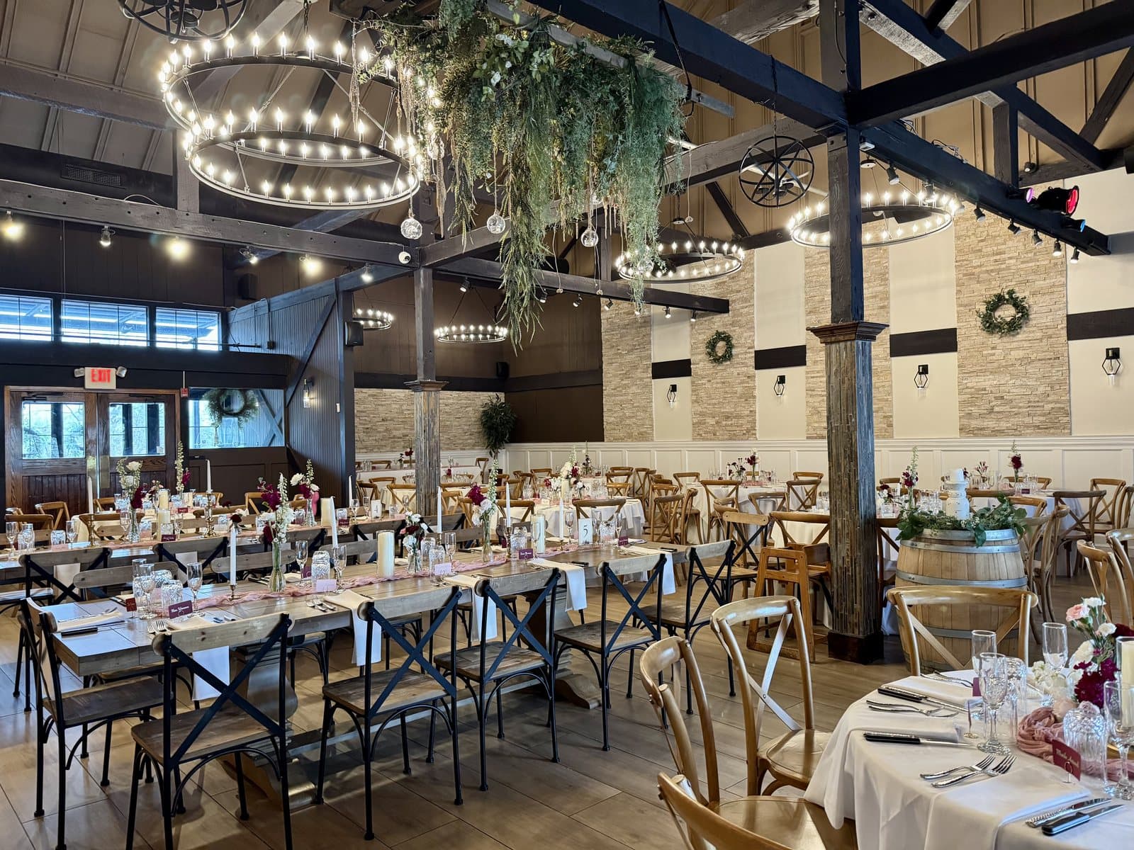 The Fox Barn at Twenty9 banquet hall set with long tables under wagon-wheel chandeliers, Malvern, PA
