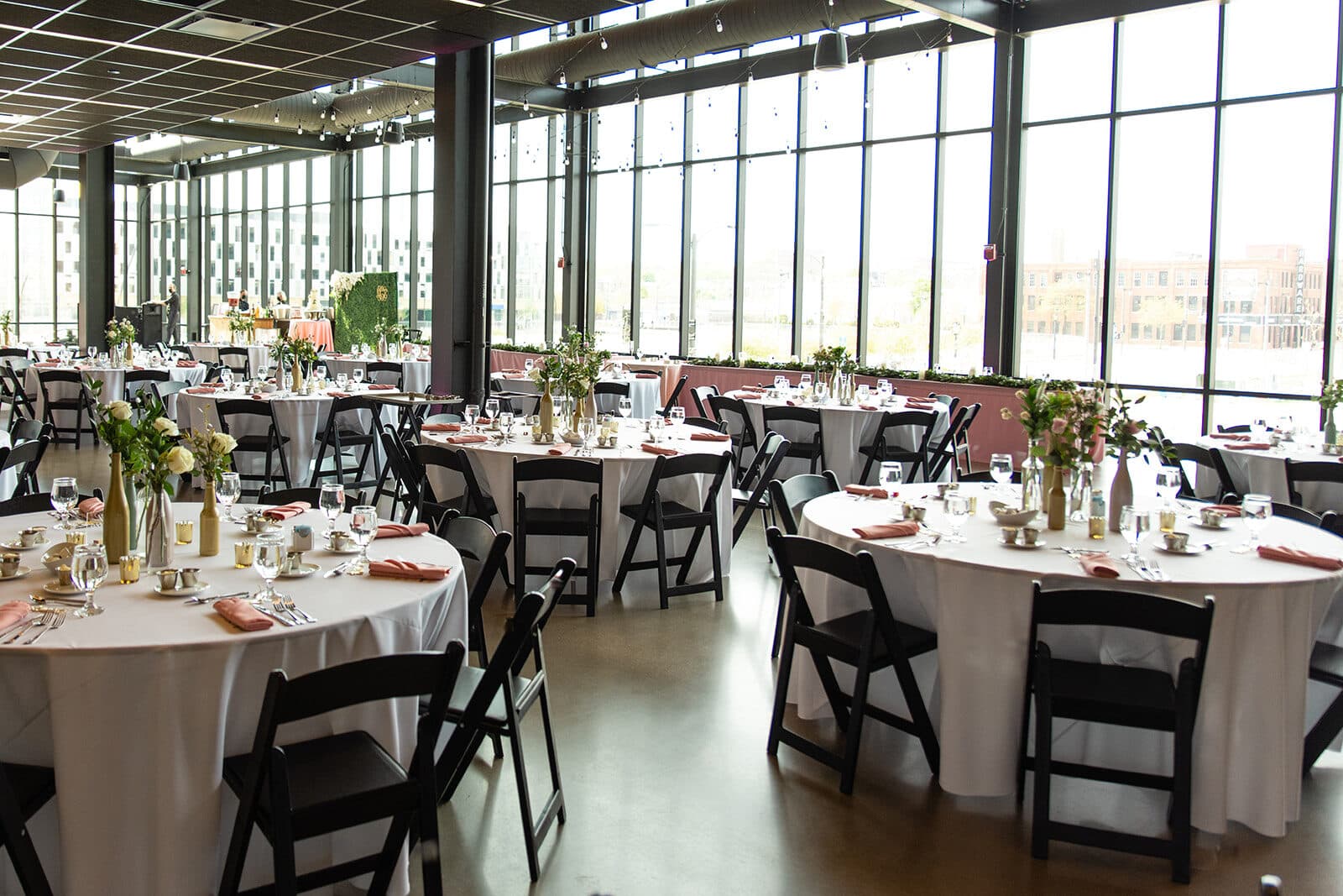 Gather at Deer District's glass-walled event hall set with round banquet tables, Milwaukee, WI