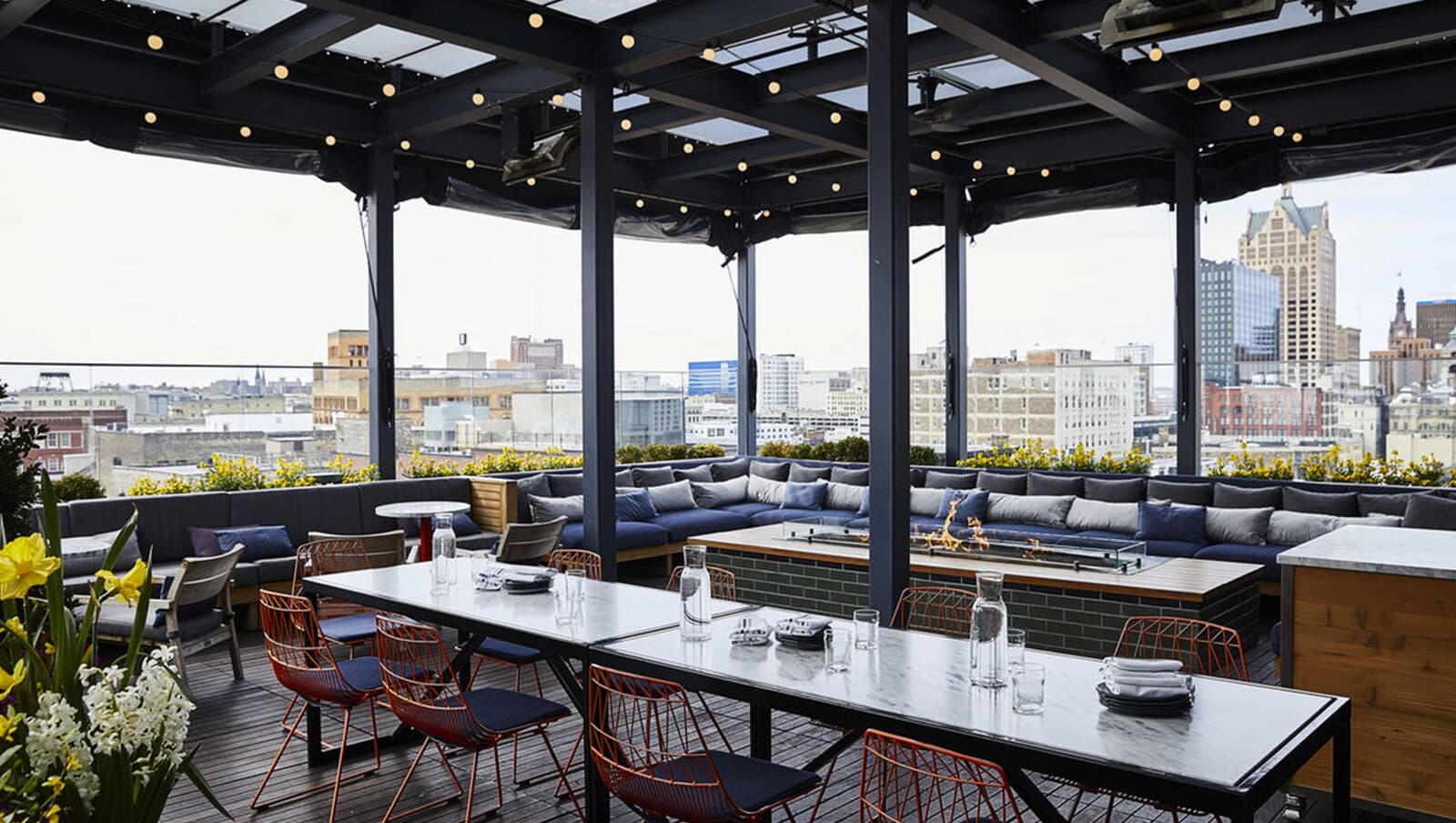 The Journeyman Hotel's rooftop terrace with long tables and a fire pit lounge above downtown, Milwaukee, WI