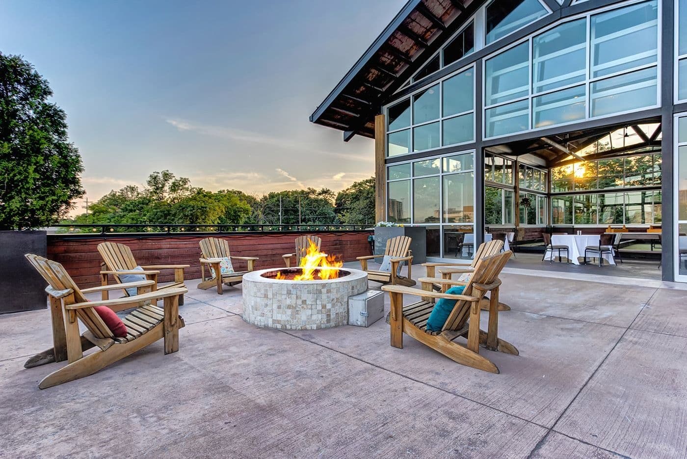 Pinstripes Oak Brook patio with Adirondack chairs around a fire pit beside the glass-walled bocce hall in Oak Brook, Illinois