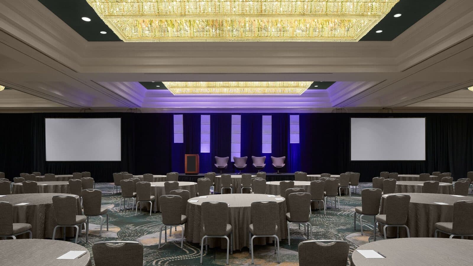 The Grand Ballroom at Hyatt Regency Reston set with round tables before a lit stage and screens, Reston, VA