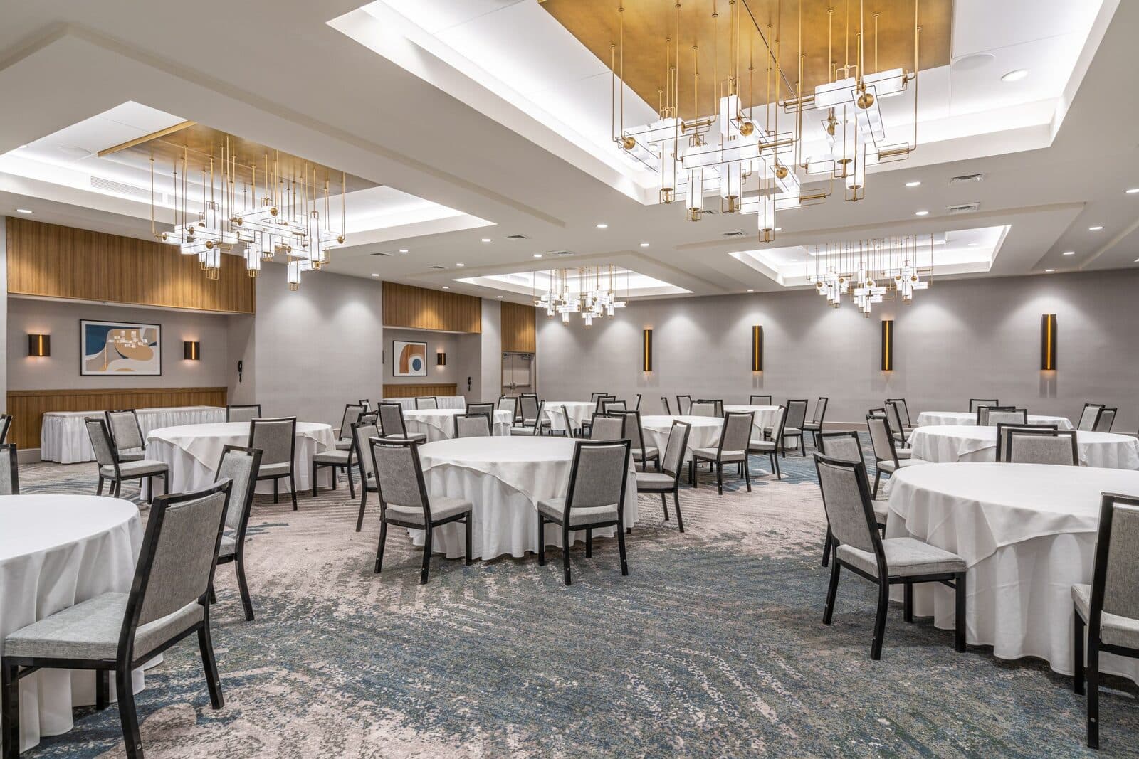 A ballroom at the Sheraton Reston Hotel set with round tables under modern chandeliers, Reston, VA
