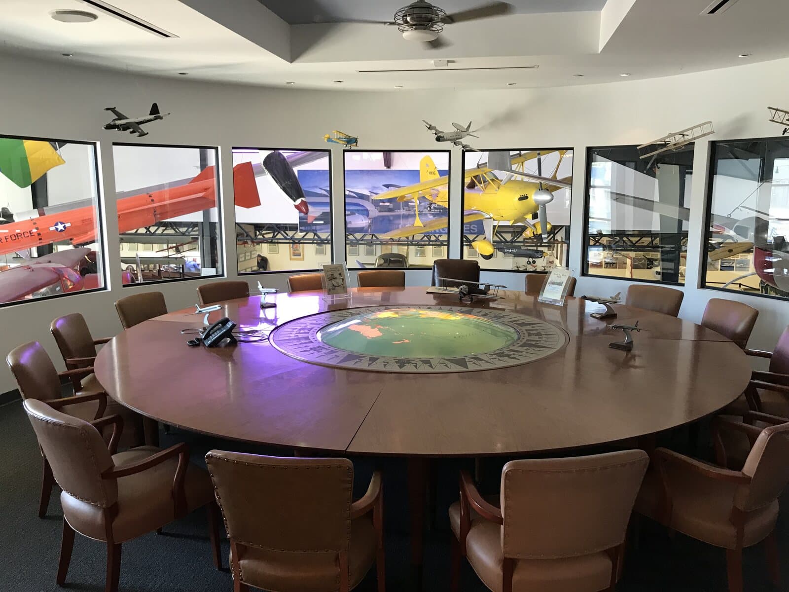 The Douglas Boardroom at the Museum of Flying, a round conference table with windows onto the hangar and its historic aircraft in Santa Monica, CA
