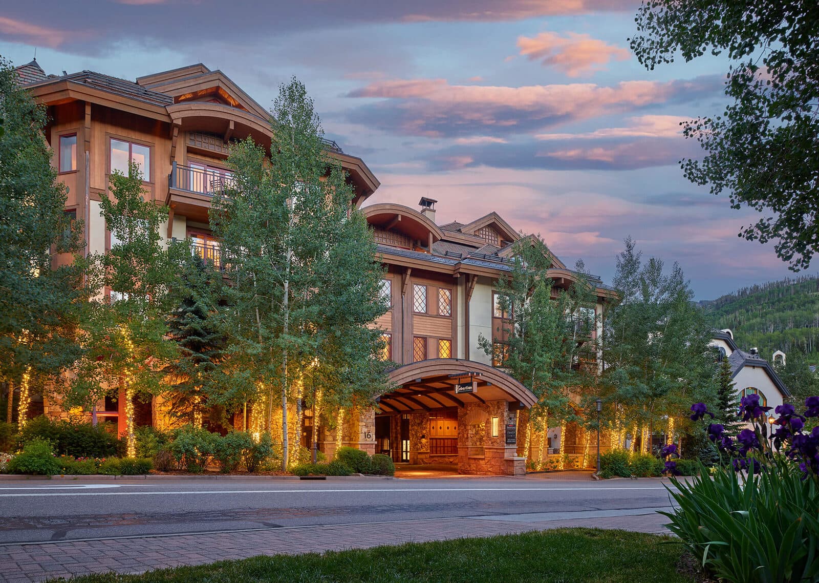 The Sebastian Vail's entrance at summer dusk, with lit aspens under a pink sky