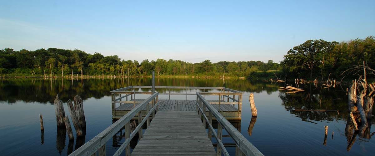 A wooden fishing pier on calm Hyland Lake with a wooded shoreline, Bloomington, MN
