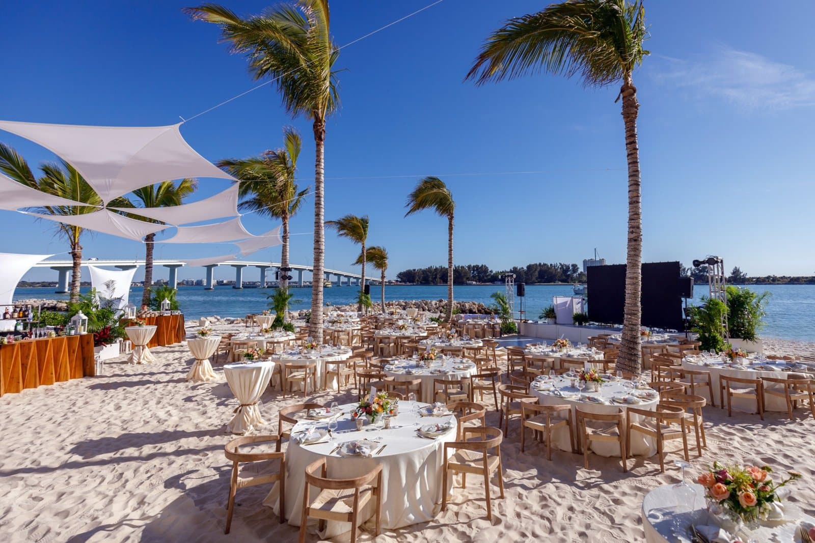 Beachfront event set with dinner rounds, shade sails and a stage at JW Marriott Clearwater Beach Resort & Spa, Clearwater Beach, FL
