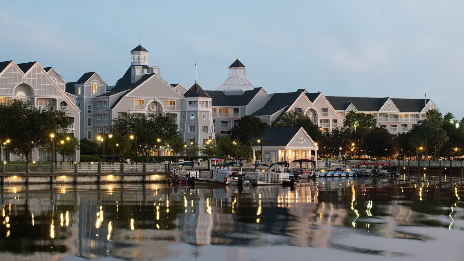 Disney's Yacht Club Resort and its marina lit at dusk across the water