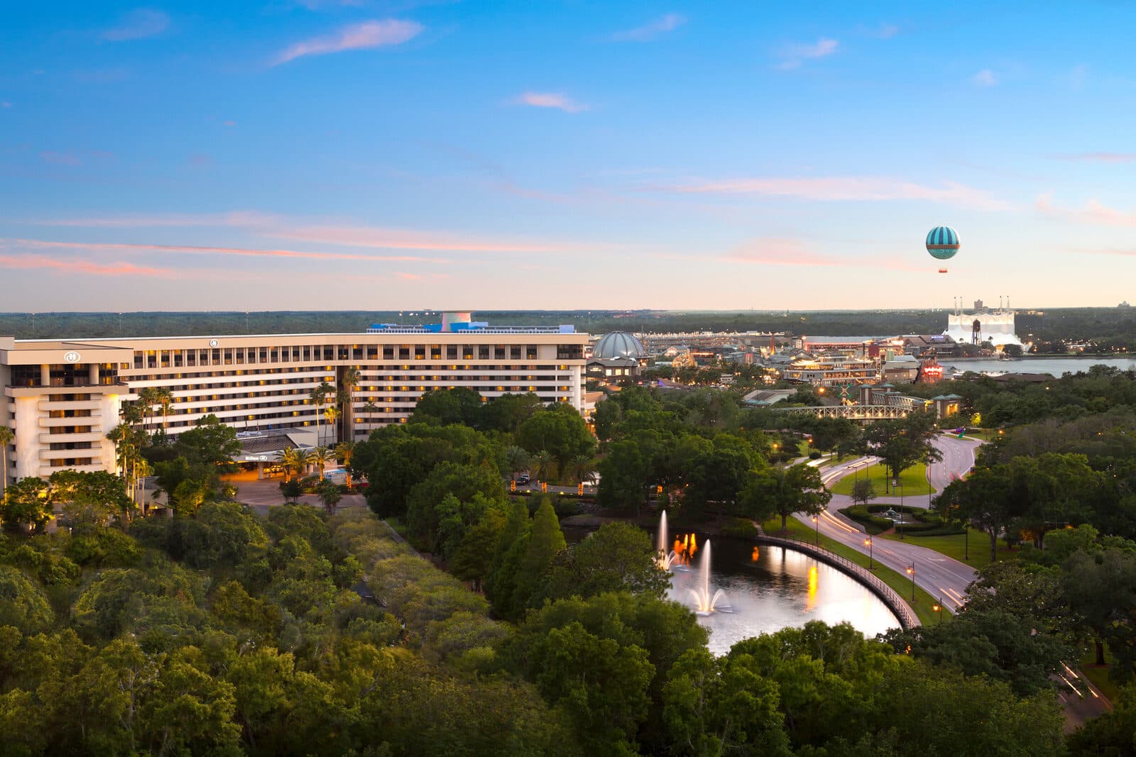 The Hilton Orlando Lake Buena Vista beside the lake and gardens, with Disney Springs and its balloon beyond