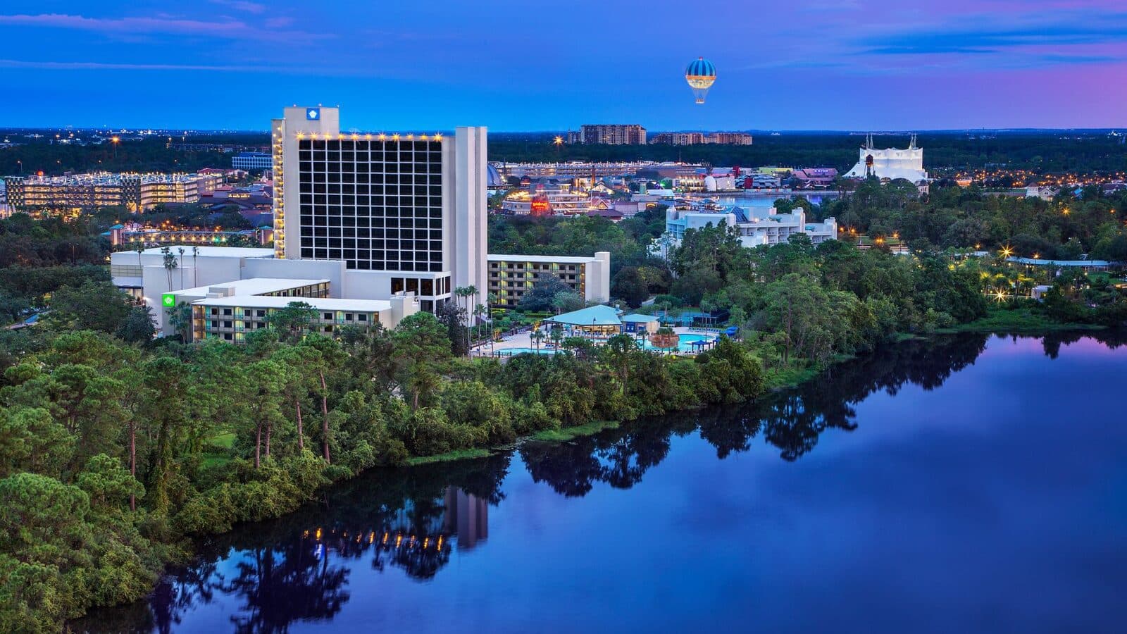 The Wyndham Lake Buena Vista resort area from the air at dusk, beside the lake, with the Disney Springs balloon in the distance