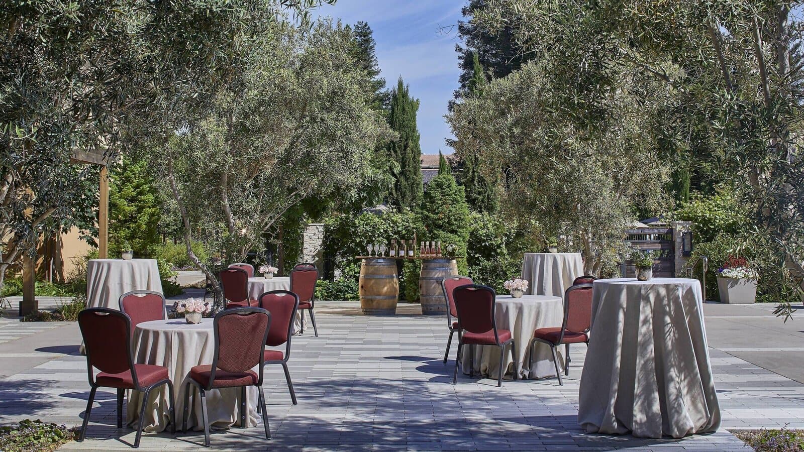 Cocktail tables and chairs set on a garden patio among olive trees at the Napa Valley Marriott Hotel & Spa in Napa, CA