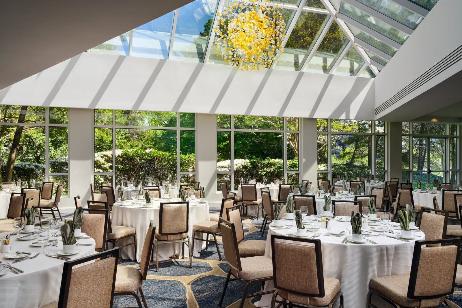 The glass-roofed event atrium at Hilton McLean Tysons Corner set with round banquet tables, McLean, VA