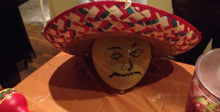 A balloon with a sombrero on it is sitting on a table.