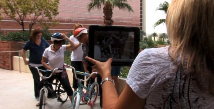 A woman takes a picture of a group of people on bicycles.
