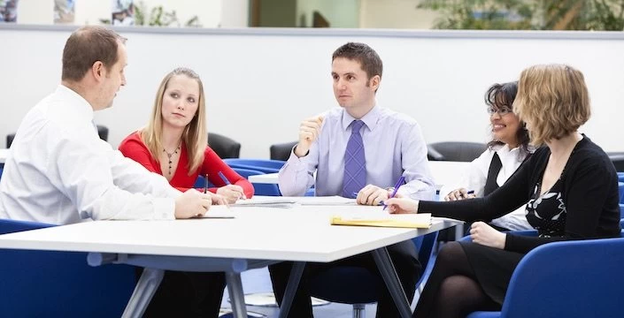 A group of people sitting around a table in an office.