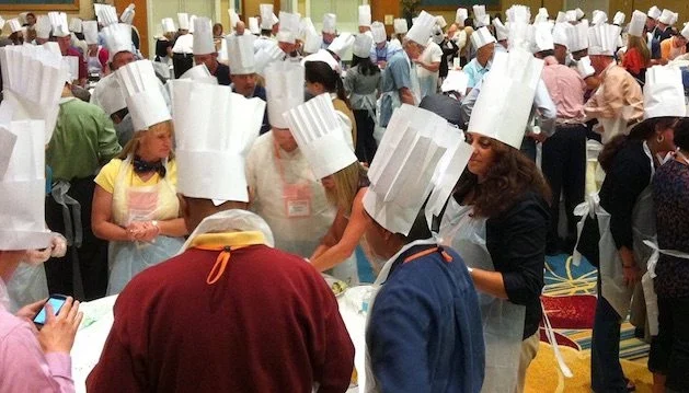 A large group of people in chef hats engaging in activities at a convention.