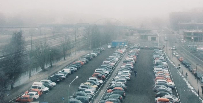Cars parked in a parking lot on a foggy day.