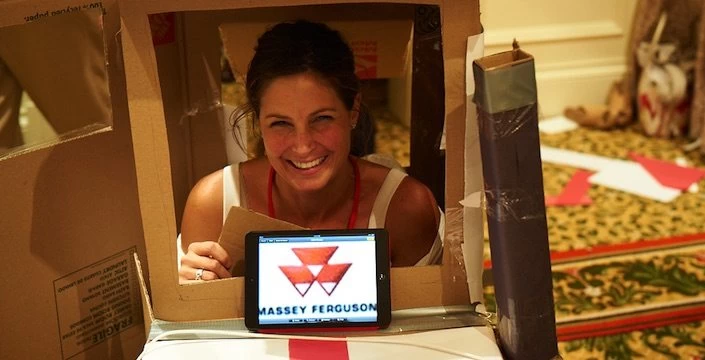 A woman in a cardboard box holding an ipad.