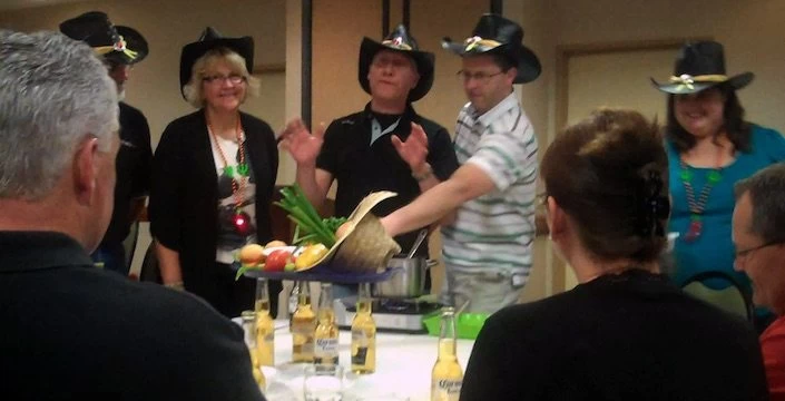 A group of people in cowboy hats standing around a table.