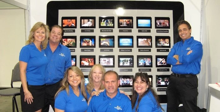 A group of people posing in front of a large screen.