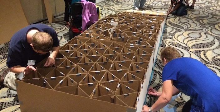 A group of people working on a large cardboard box.