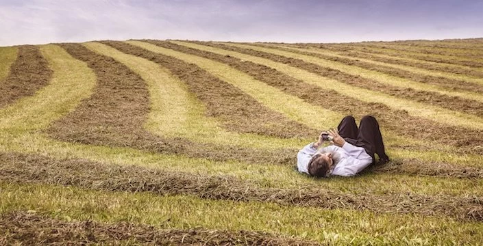 A man is laying down in a field of hay.