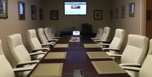 A conference room with white chairs and a tv.