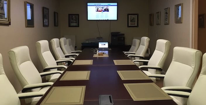 A conference room with white chairs and a tv.