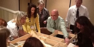 A group of people standing around a table looking at a box.