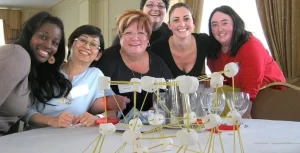 A group of women posing for a picture with a model of a structure.