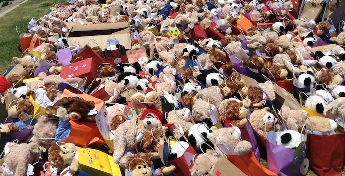 A large group of teddy bears are sitting on a grassy area.