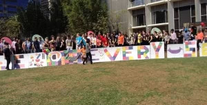 A group of people standing in front of a colorful sign.