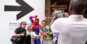 A group of people taking pictures of a spider - man in front of a sign.