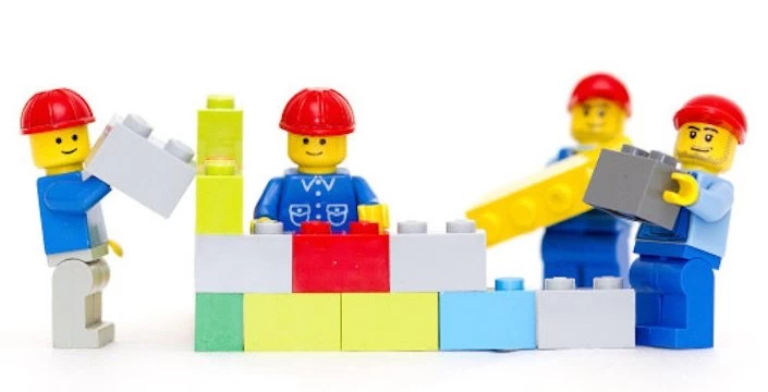 A group of lego construction workers are working on a block.