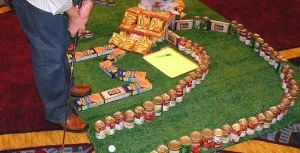 A man is standing next to a golf course made out of cans.