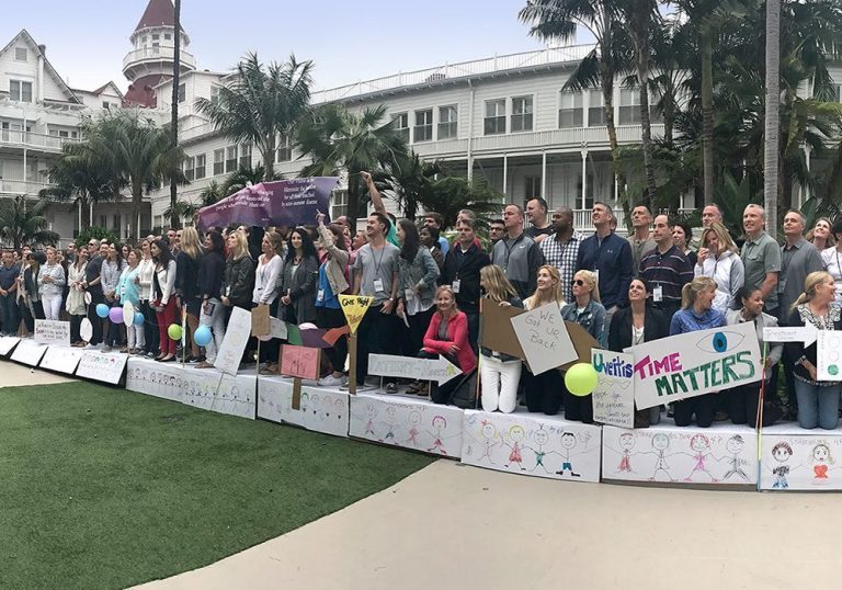 A group of people holding signs in front of a hotel.