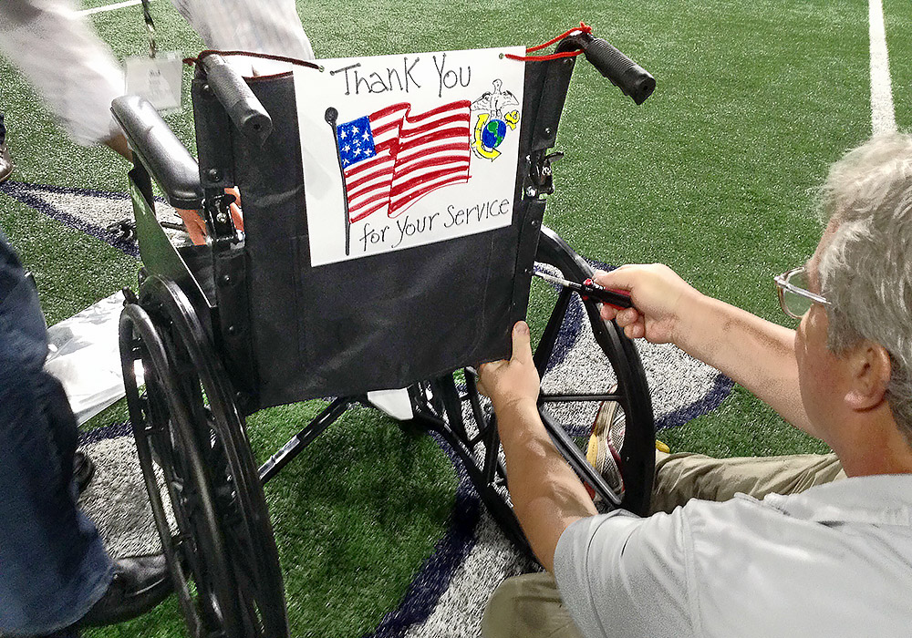 A man in a wheelchair with a thank you sign.
