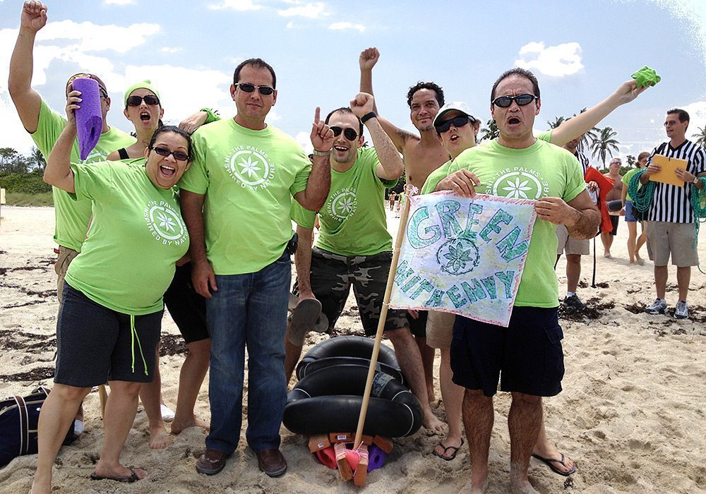 A group of people in green shirts posing on the beach.