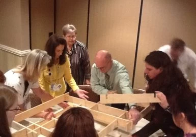 A group of people working on a wooden frame.