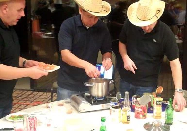 Three men in cowboy hats preparing food at a table.