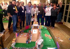 A group of people posing in front of a model of a city.