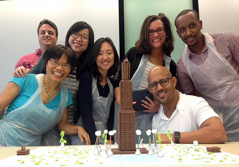 A group of people posing in front of a chocolate tower.