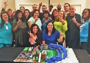 A group of people posing in front of a cake.