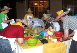 A group of people in mexican hats preparing food at a table.