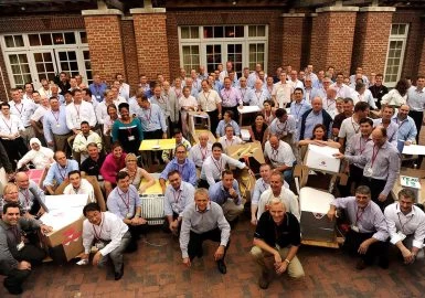 A group of people posing for a picture in front of a brick building.